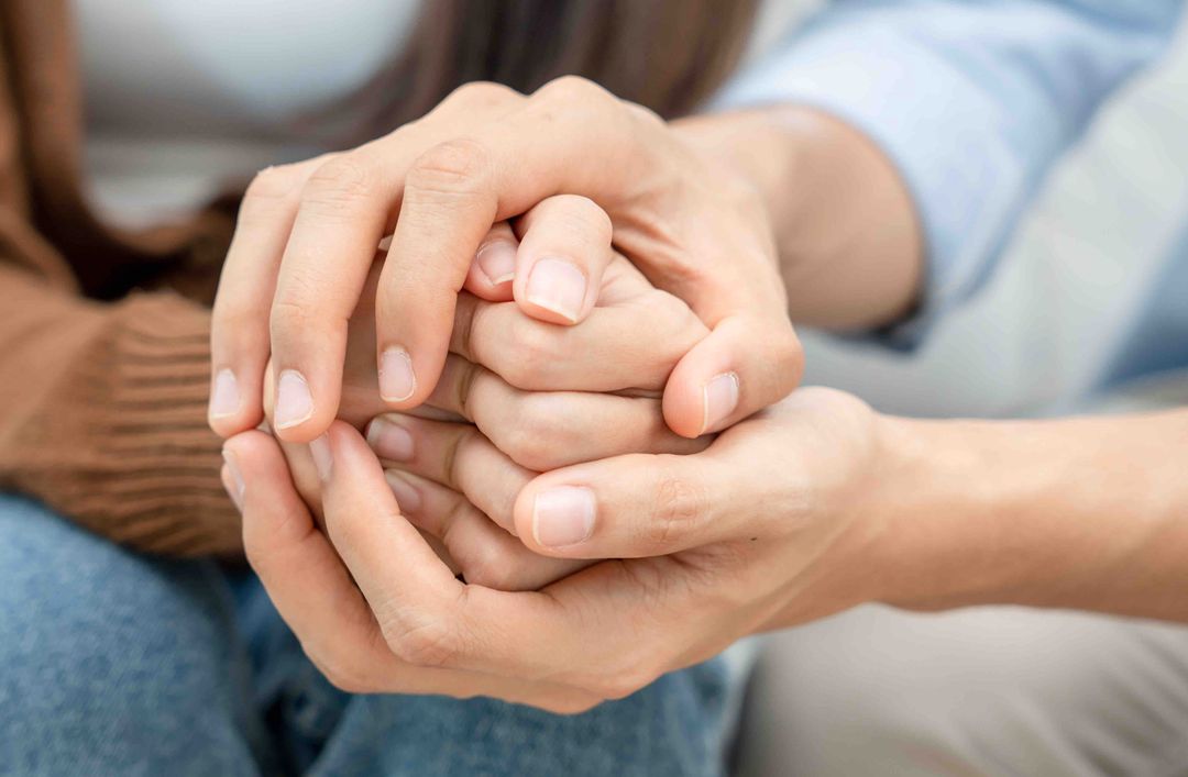 Two pairs of hands holding each other warmly