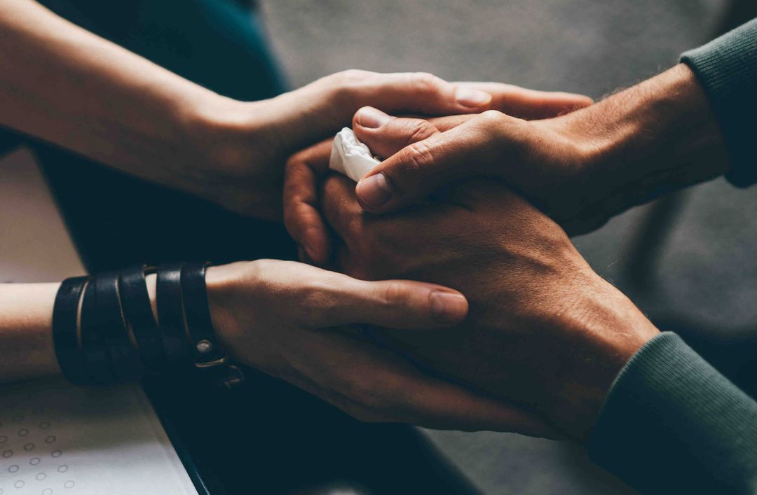 Two people holding hands together in a comforting gesture