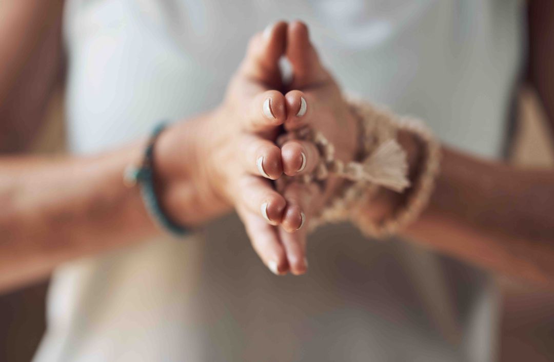 Clasped hands in a prayer position with a beaded bracelet